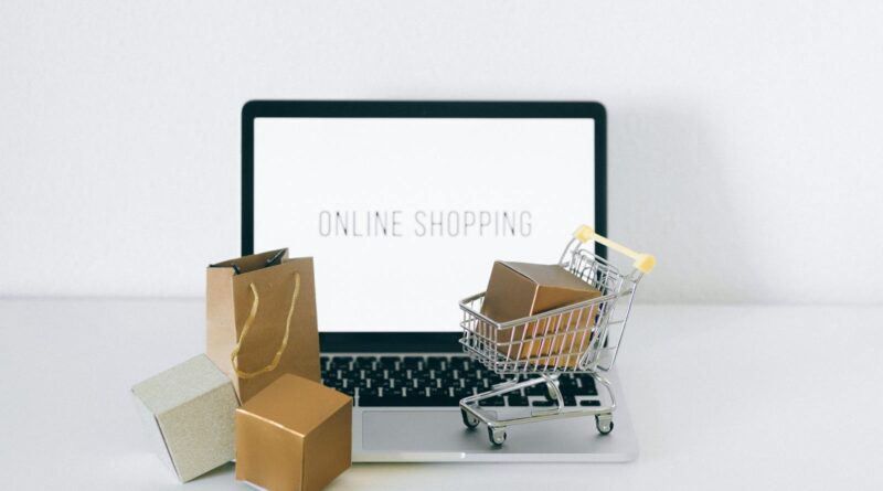 Ordinateur portable affichant des achats en ligne avec des boîtes et un panier, représentant le commerce électronique.