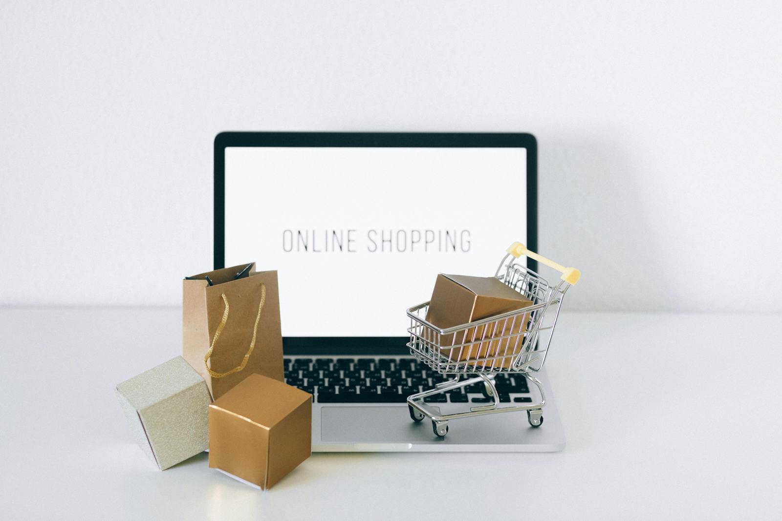 Ordinateur portable affichant des achats en ligne avec des boîtes et un panier, représentant le commerce électronique.