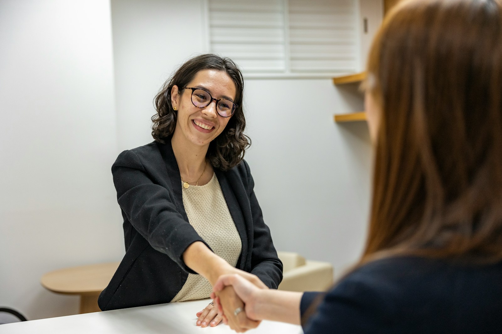 une femme serrant la main d'une autre femme assise à une table